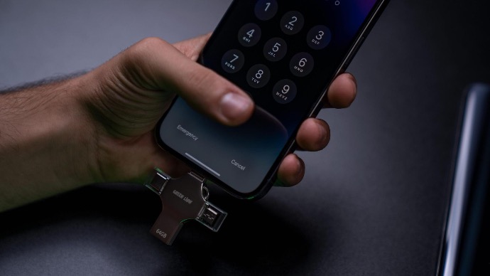 alt="A man holding smartphone and USB Flash Drive connected "